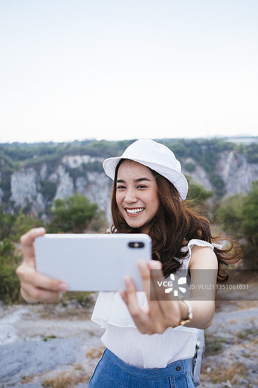 美丽的亚洲泰国女旅行者在自然中使用智能手机自拍。图片素材