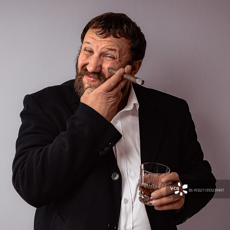 靠墙喝酒时抽雪茄的男人图片素材