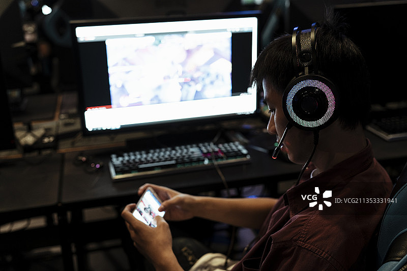 年轻的亚洲玩家厌倦了在PC上玩游戏，所以他拿起智能手机玩游戏。图片素材