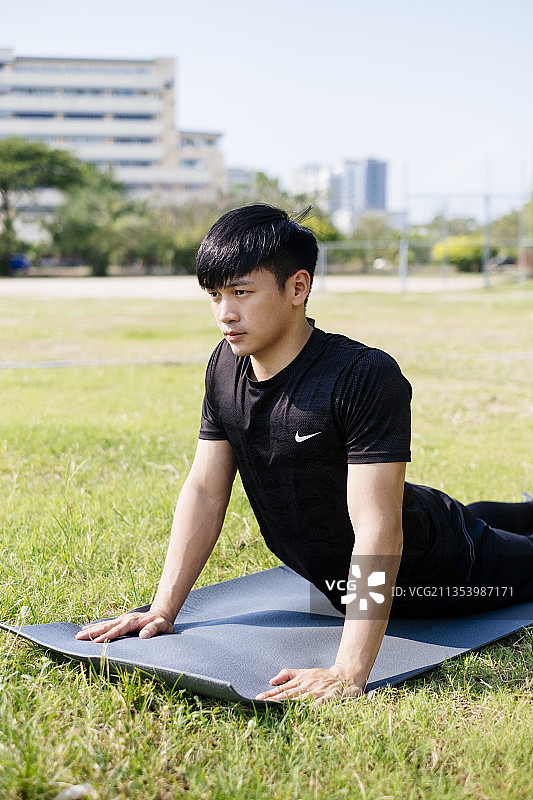运动亚洲泰国人在绿色场地上做瑜伽在黑色运动服。在户外。图片素材