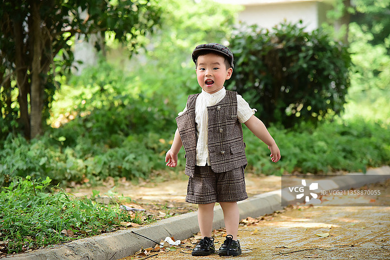 阳光下林荫小路上穿着短袖西服玩耍的小男孩图片素材