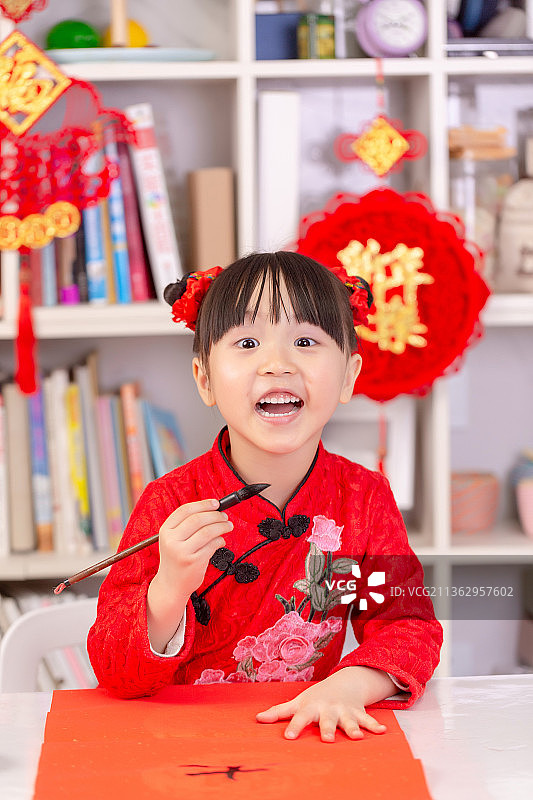 穿旗袍的中国小女孩过新年写对联图片素材