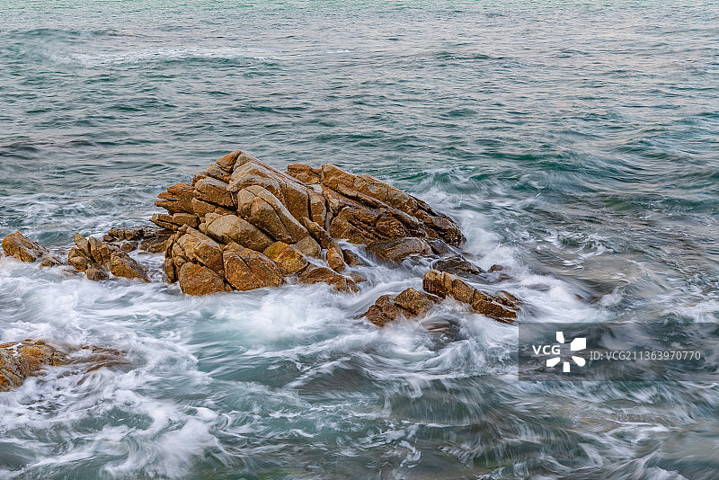 深圳大梅沙海滨公园栈道沙滩边的礁石和风浪图片素材