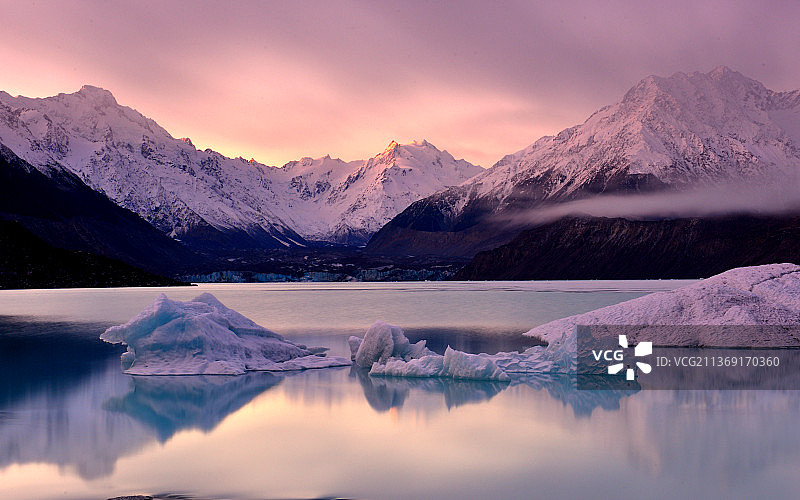 在新西兰坎特伯雷，当冰川触碰到害羞的风景，在夕阳下，由雪山映衬天空的湖图片素材