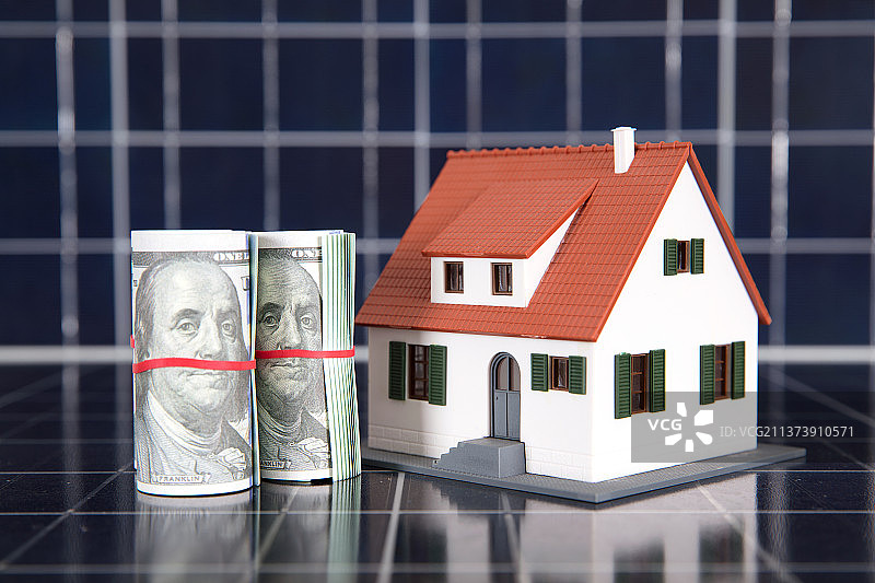 太阳能板背景上的美元钞票和房屋模型图片素材