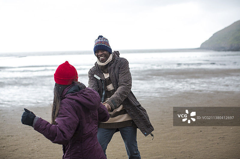 在潮湿的冬季海滩上快乐玩耍的夫妇图片素材