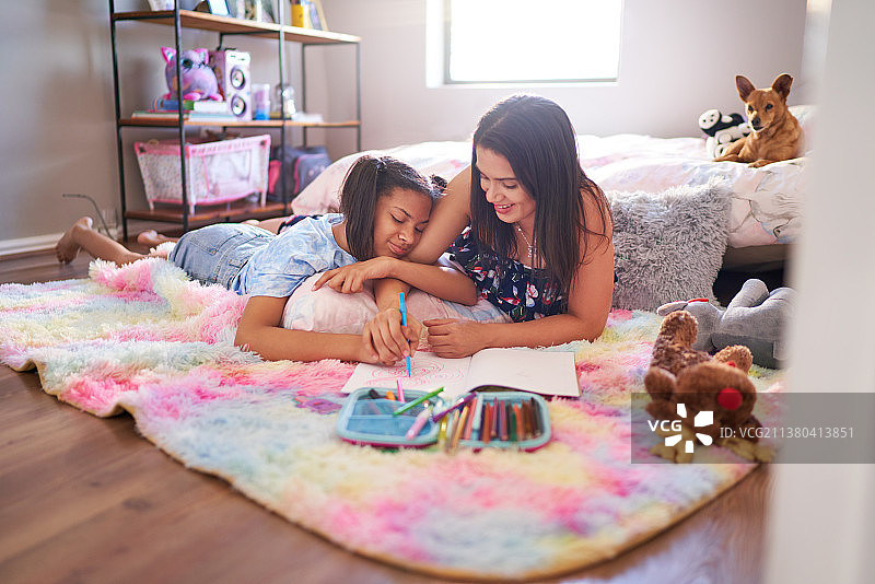 母亲和女儿在卧室的地毯上画画图片素材