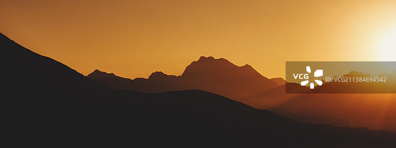 阳光穿过山脉，日落时山的剪影的风景，斯瓦特高速公路，巴基斯坦图片素材