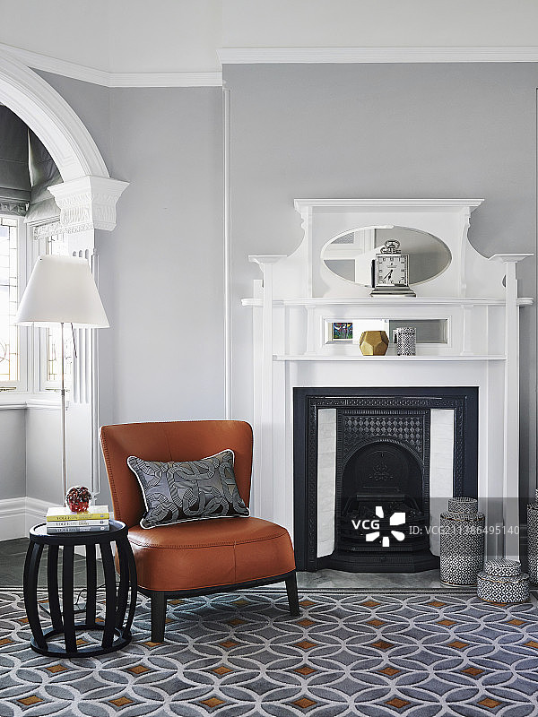 客厅里的壁炉前摆放着干邑色的皮椅和边桌，墙是浅灰色的图片素材