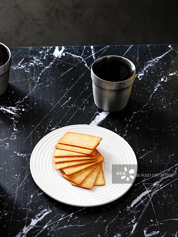黑色花岗岩桌面上摆放着饼干和饮品咖啡图片素材