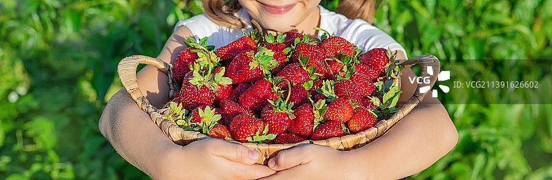 一个手里拿着草莓的孩子选择性聚焦图片素材
