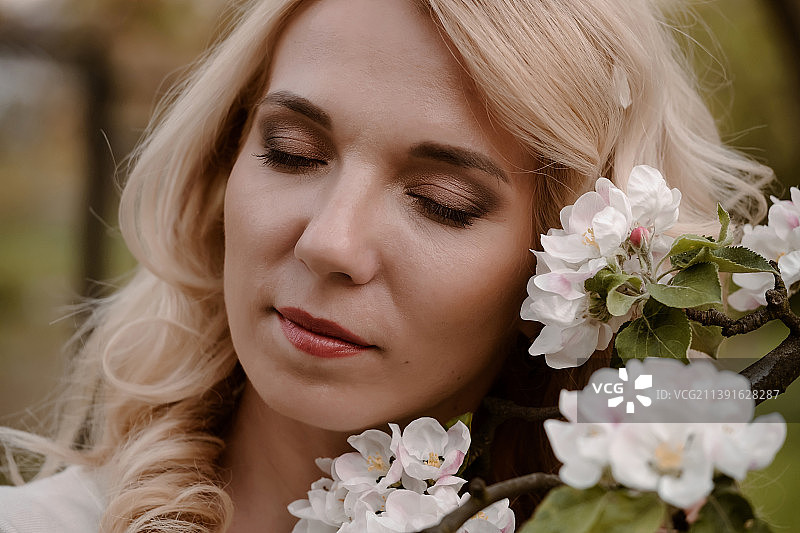 女子肖像与眼睛闭上享受开花的春天图片素材