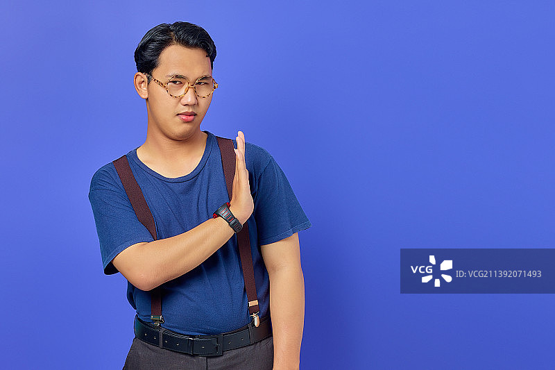 印度尼西亚，一名紧张焦虑的年轻亚洲男子在紫色背景上做着停止不动的手势图片素材