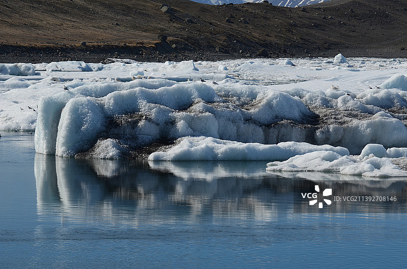 湖泊中的冰山，在它的一侧显示出一些沉积物图片素材