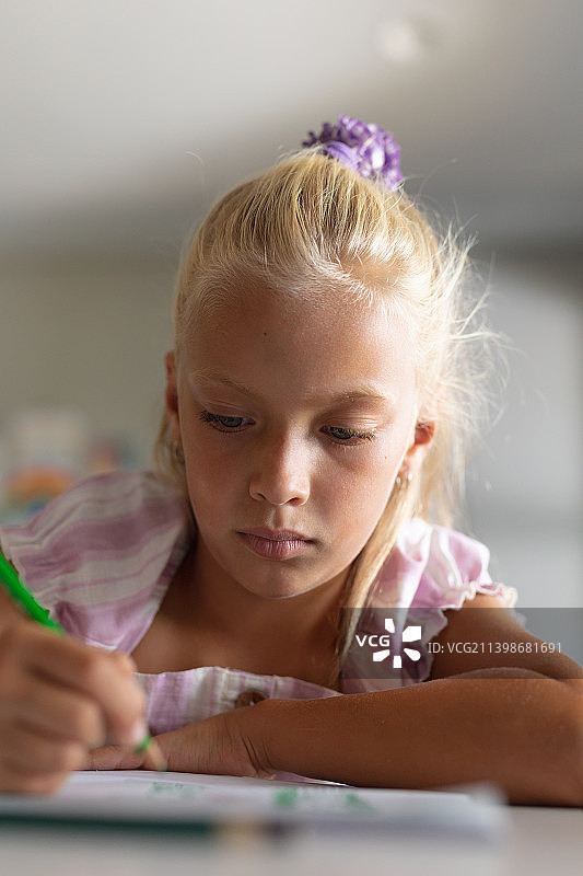 白人小学女生在课桌上画书的特写图片素材
