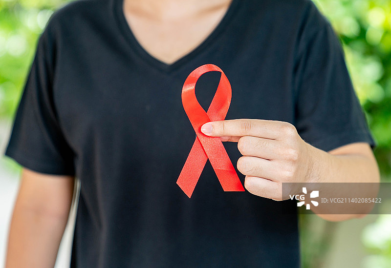 身穿黑衬衫的男子手持红丝带，为泰国抗击艾滋病而战图片素材