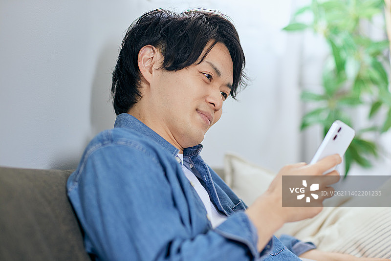 日本男子在沙发上使用智能手机图片素材