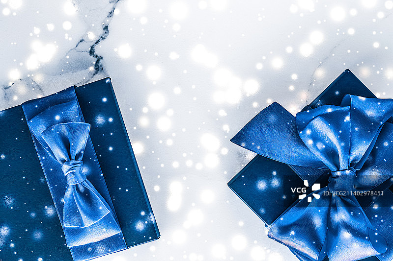 冬至礼盒配蓝色丝绸蝴蝶结，雪花在大理石上闪闪发光图片素材