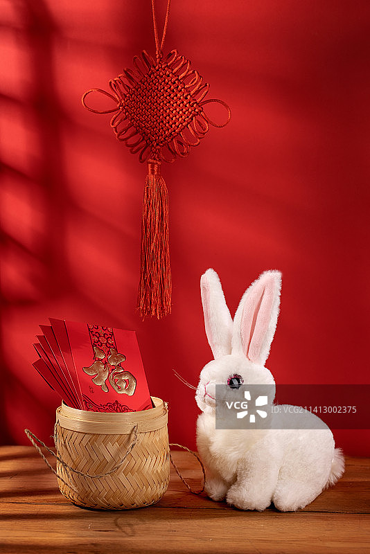 在红色背景里的小兔子和红包中国结图片素材