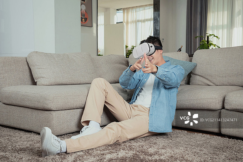 坐在地毯上玩VR的年轻男人图片素材