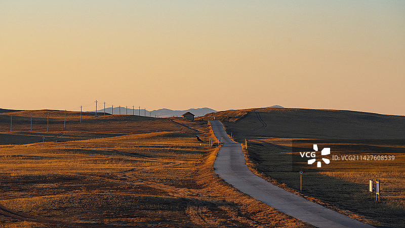 夕阳下呼伦贝尔草原上通往呼伦湖成吉思汗拴马桩的公路图片素材