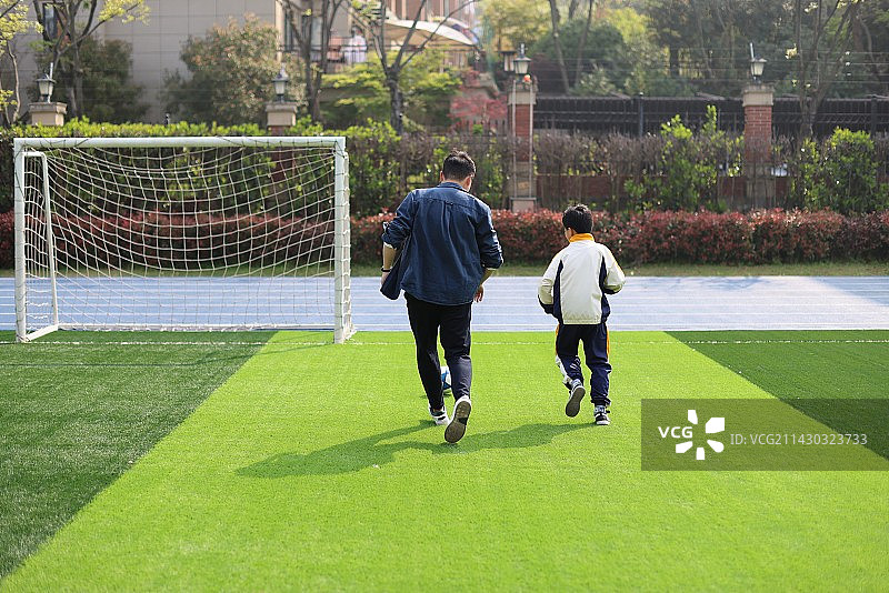 父亲和儿子在足球场上踢球图片素材