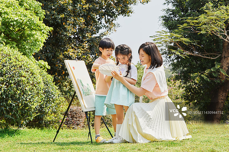 母子三人在草坪上练习画画图片素材
