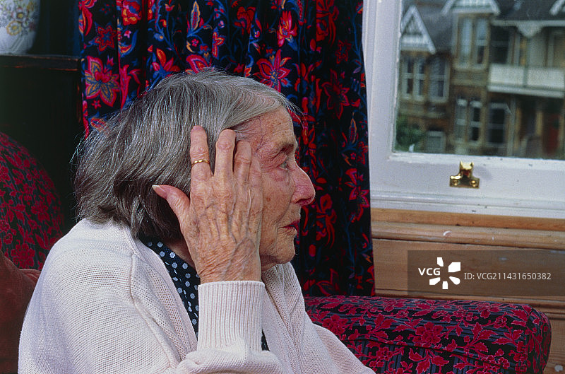 孤独:老妇人凝视着窗外图片素材