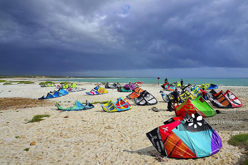欧洲意大利撒丁岛奥里斯塔诺省西尼斯半岛的海滩上，风筝和风筝冲浪者在强风中冲浪图片素材
