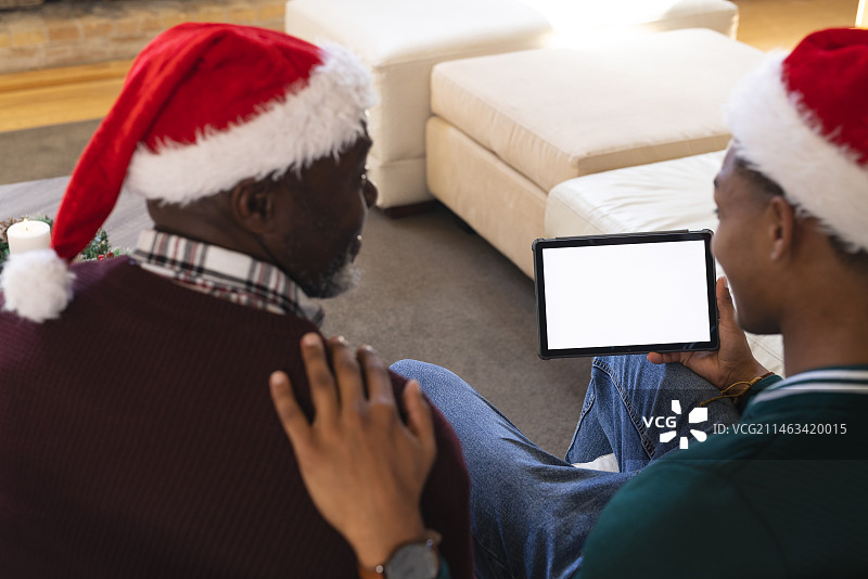 非裔美国人父亲和儿子圣诞节平板电脑视频通话，复制空间屏幕图片素材