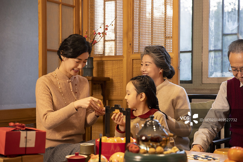 东方家庭过年：奶奶、妈妈和小女孩在客厅围炉煮茶、聊天嬉戏图片素材