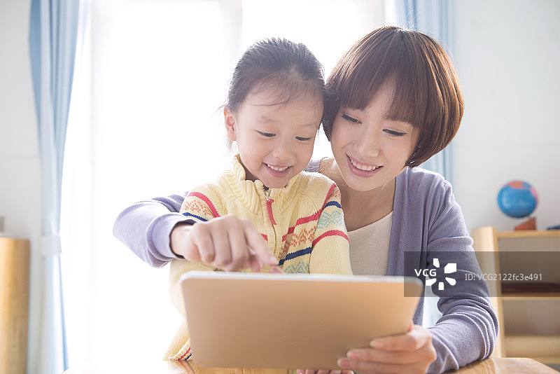 Kindergarten teacher and girl using tablet图片素材