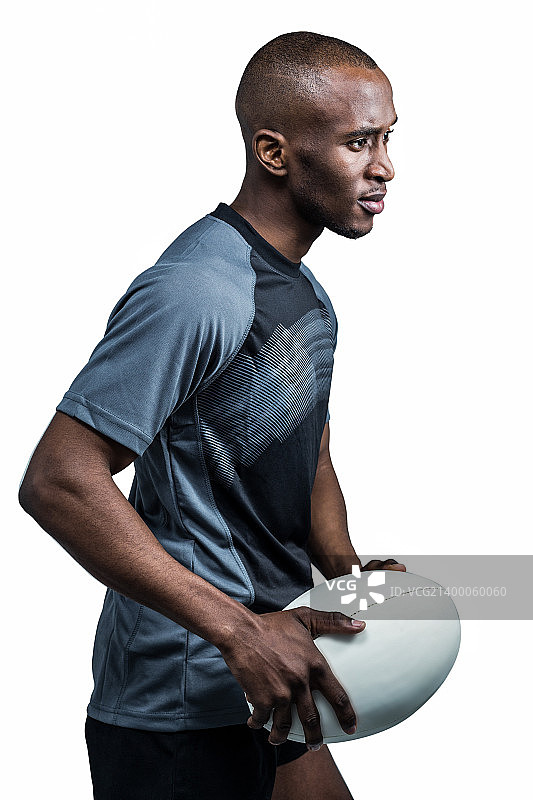 一个自信的运动员拿着橄榄球站在白色的背景下图片素材