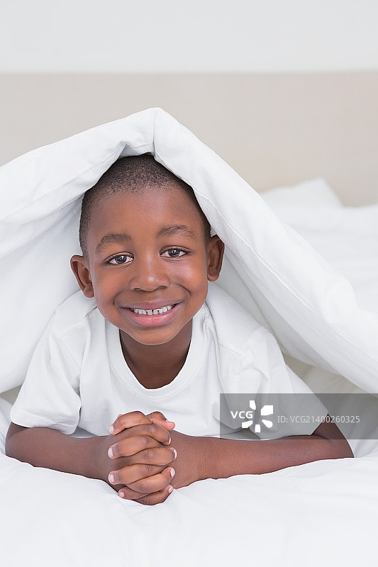 漂亮的微笑小男孩在床上在家里的卧室图片素材