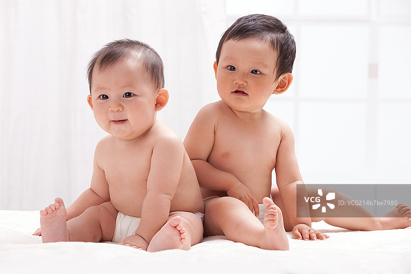 两个婴儿坐在室内床上图片素材