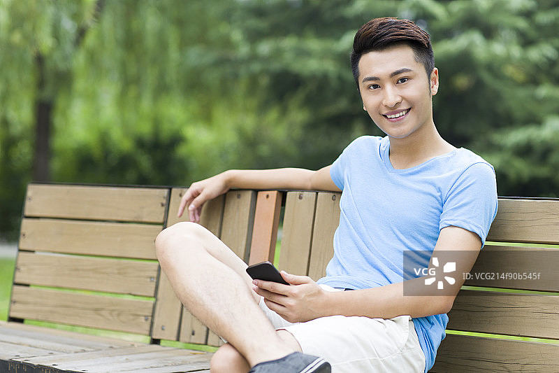 年轻男子坐在公园长椅上图片素材