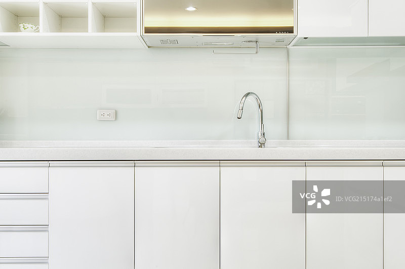 Silver arched mixer tap and sink in white modern kitchen图片素材