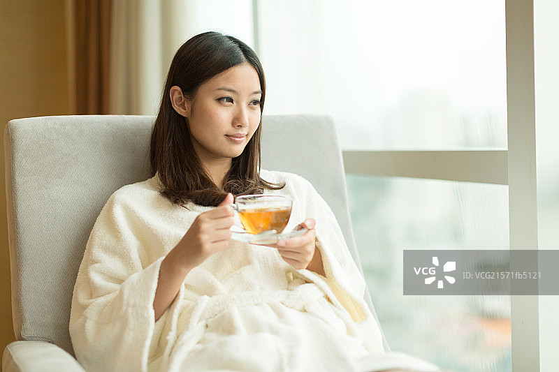 年轻女孩在窗前喝茶图片素材