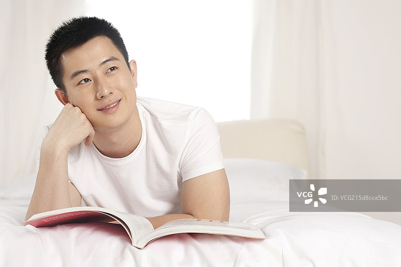 躺在床上看书的青年男性图片素材