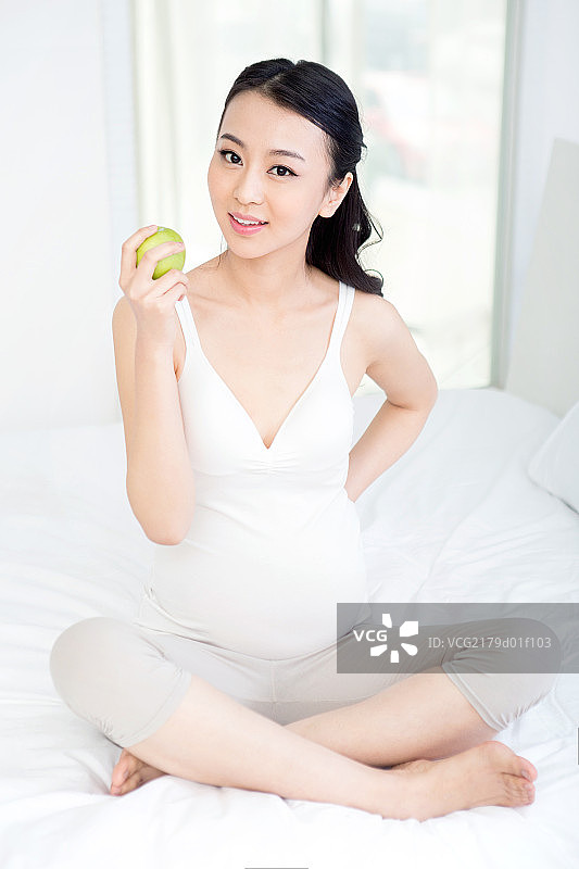 坐在床上拿苹果的孕妇图片素材
