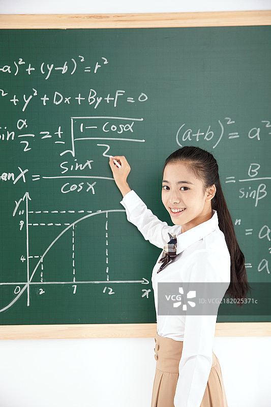 中学女生在黑板前写数学公式图片素材