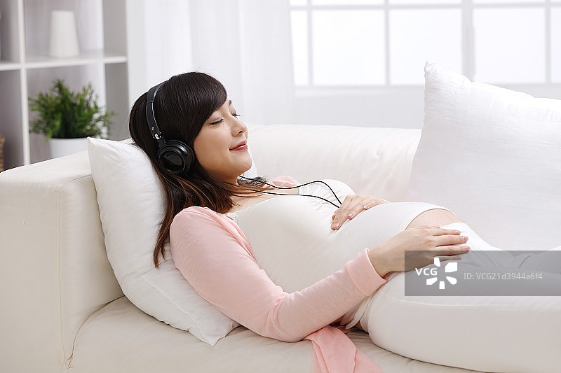 孕妇躺在沙发上听音乐图片素材