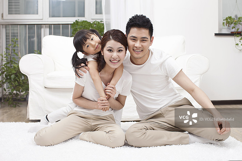 三口之家坐在在白色地毯上快乐合影图片素材