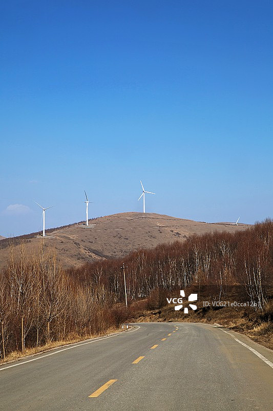 山坡山的风力发电站和输电塔图片素材