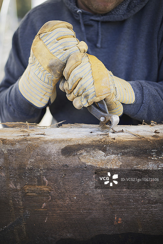 一个回收木材作坊。一个人拆除了所有的钉子和大头钉，准备木材。图片素材