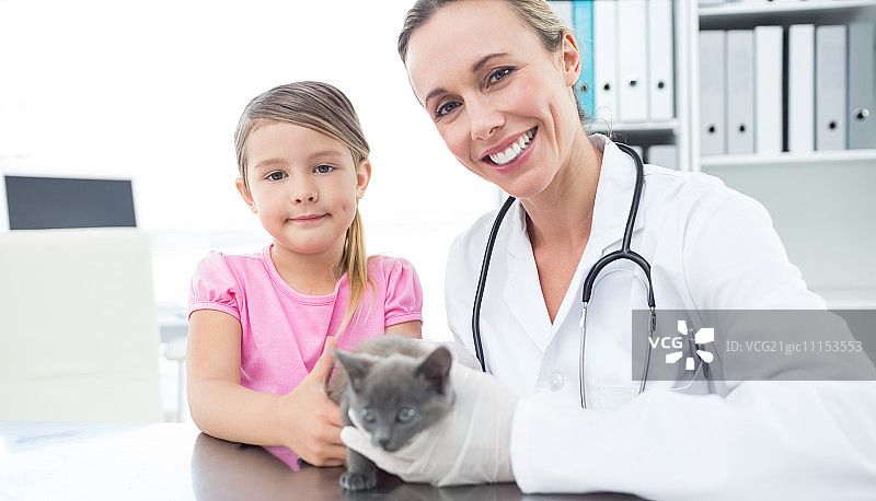 肖像女兽医和女孩与小猫在诊所图片素材