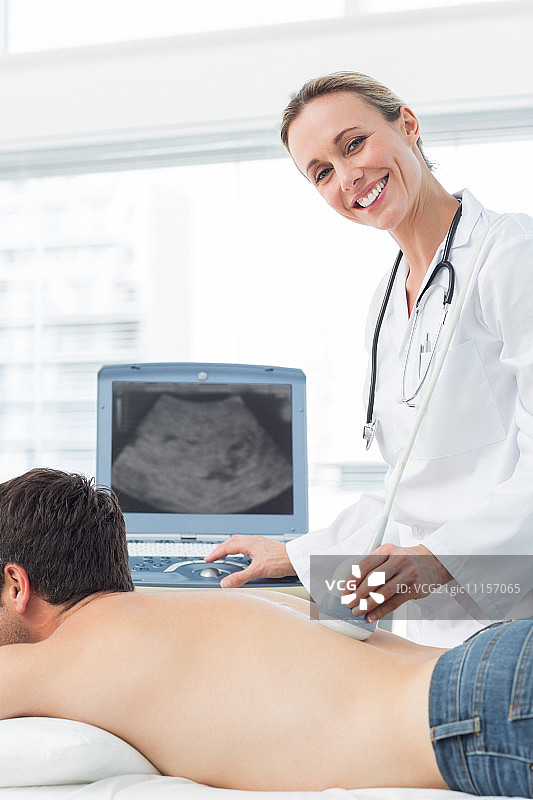 快乐的女医生在男病人的背部做超声波扫描图片素材