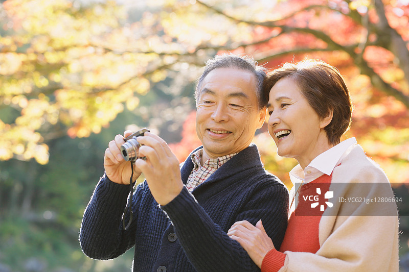 秋天，一对日本老年夫妇在一个传统公园里拍照图片素材