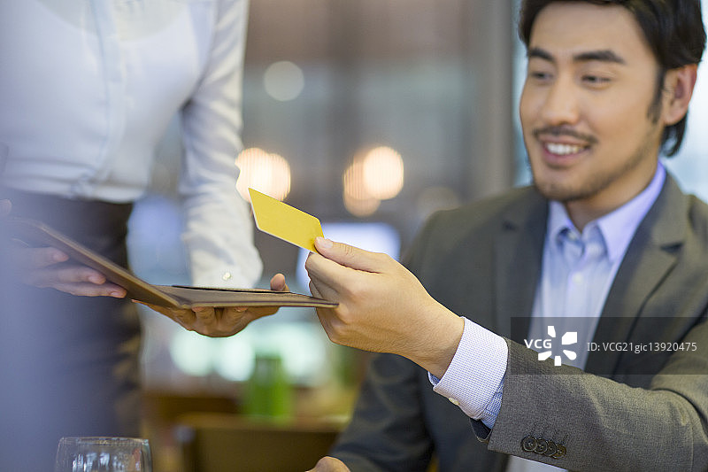 商务男士在餐馆使用信用卡结账图片素材