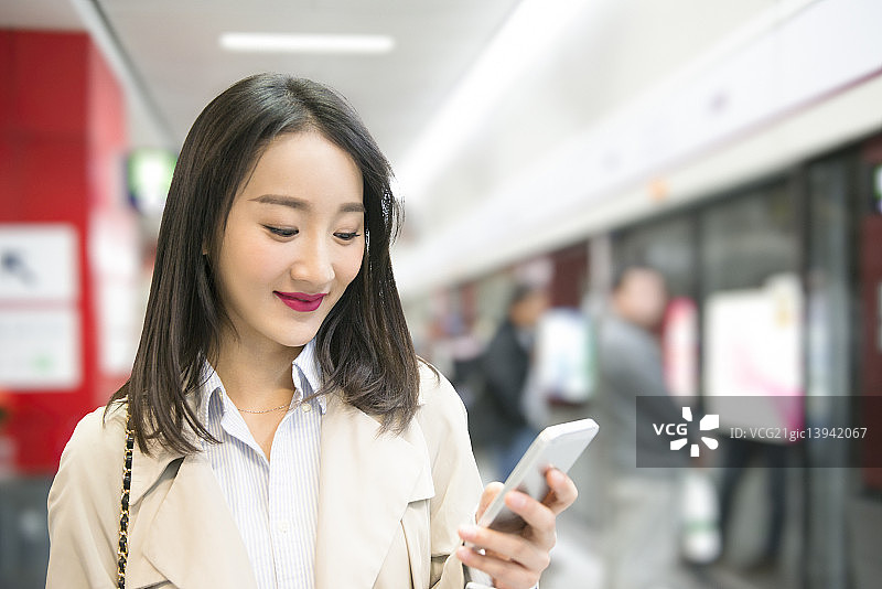 Businesswoman using smart phone at subway station图片素材